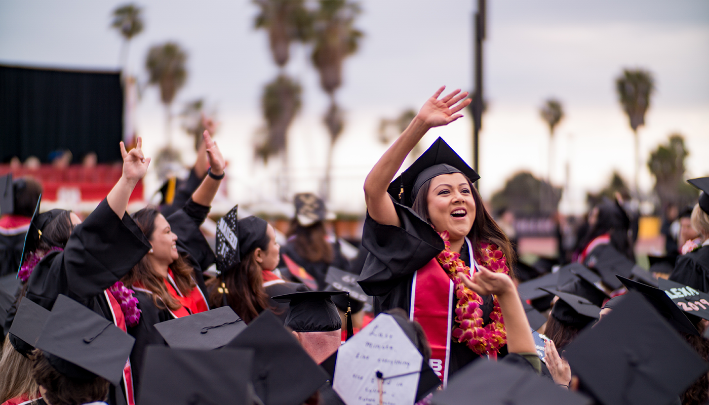 Santa Barbara City College student graduating and waving to family.